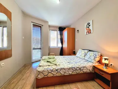 a bedroom with a bed and a dresser and two windows at Mezonet - Sol Casa in Lazur in Burgas City
