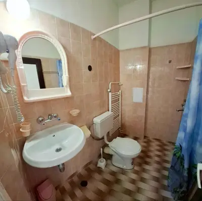 a bathroom with a sink and a toilet and a mirror at Hotel Bobchev in Sozopol