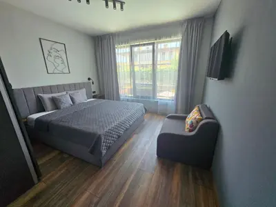 a bedroom with a bed and a chair and a window at Villa Felicity, private pool with heating and salt water in Lozenets
