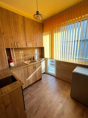 a kitchen with wooden cabinets and a large window at Varna Top Central Apartment-Tulip in Varna City