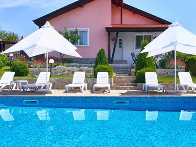 a pool with chairs and umbrellas next to a house at BulgariaVilla - Royal Villas in Bryastovets