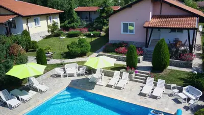a pool with chairs and umbrellas next to a house at BulgariaVilla - Royal Villas in Bryastovets
