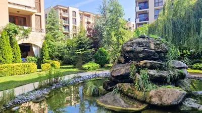 a garden with a pond and rocks and buildings at Attractive Studio-Apartment in Sunny Beach Cascadas Family Resort in Sunny Beach