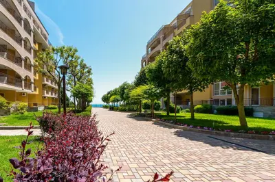 a brick walkway in a park with trees and buildings at Midia Holiday Apartments in Aheloy