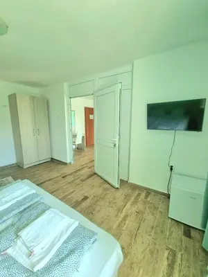 a white bedroom with a bed and a tv at Hotel Char in Primorsko