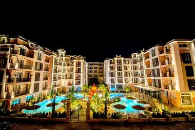 a large apartment building with a large swimming pool at night at Menada Romance Marine Apartments in Sunny Beach