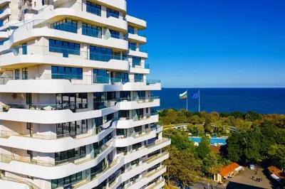 a tall white building with the ocean in the background at Cosy apartment near the beach with terrace & sea view in Burgas City