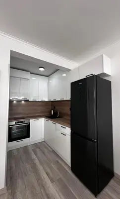 a kitchen with a black refrigerator and white cabinets at Prestige Apartment 1 in Burgas City