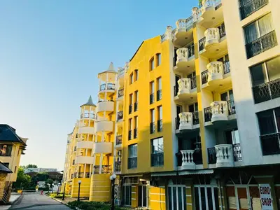 a yellow apartment building with balconies on a street at VICTORIA RESIDENCE Two Bedroom Sunny Beach in Sunny Beach