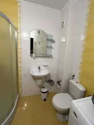 a white bathroom with a toilet and a sink at Sunset Apartment Pomorie in Pomorie