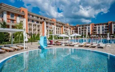 a swimming pool at a resort with chairs and umbrellas at Prestige Fort Beach - Menada Apartments in Sveti Vlas