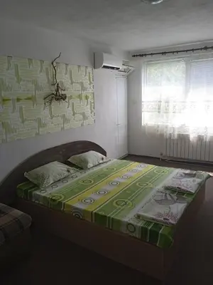 a bedroom with a bed with a green and white comforter at Къща за гости in Primorsko