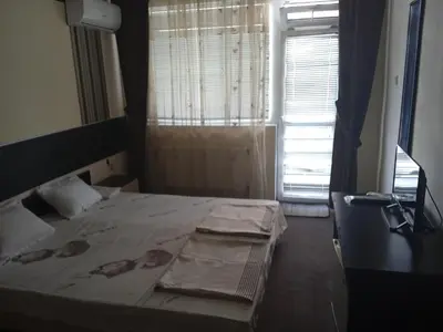 a bedroom with a bed and a window with curtains at Къща за гости in Primorsko