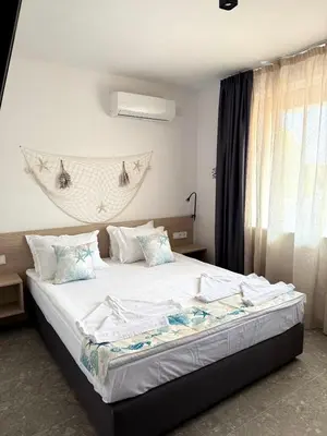 a bedroom with a bed with white sheets and blue pillows at Hotel Mistral in Nesebar