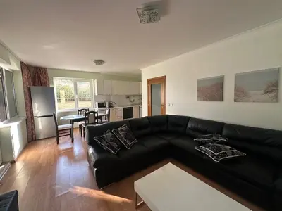 a living room with a black couch and a kitchen at Apartment Sunny Seasons Byala in Byala