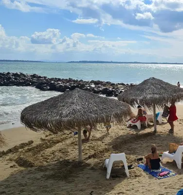 a group of people sitting under umbrellas on a beach at Apartament w Bułgarii in Sveti Vlas