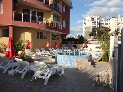 a resort with a pool and chairs and a building at Sunny Flower Family Hotel in Sunny Beach