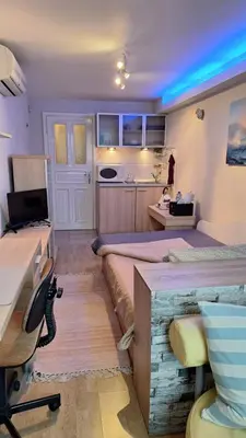 a room with two beds and a desk and a kitchen at Лазуро in Burgas City