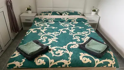 a bedroom with a bed with green and white comforter at Sunrise Sea Garden in Burgas City