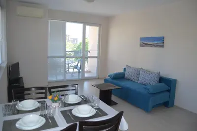 a living room with a table and a blue couch at Divela 3 Apartments in Nesebar