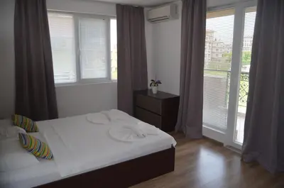 a bedroom with a bed with white sheets and windows at Divela 3 Apartments in Nesebar