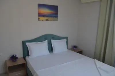 a bed with white pillows and a picture on the wall at Divela 3 Apartments in Nesebar