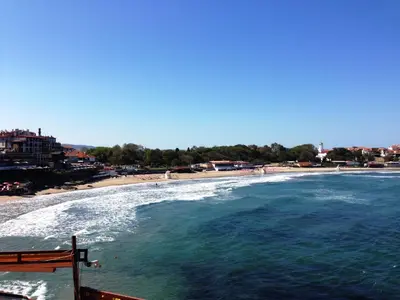 a view of a beach with a bench and the water at Hotel Parnasse in Sozopol