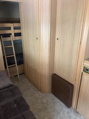 a small bedroom with a bunk bed and a ladder at Каравана Макси in Chernomorets
