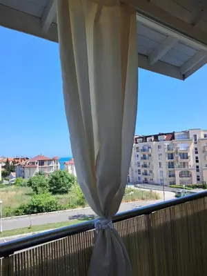 a curtain on a balcony with a view of the ocean at Small sea sunrise in Sveti Vlas