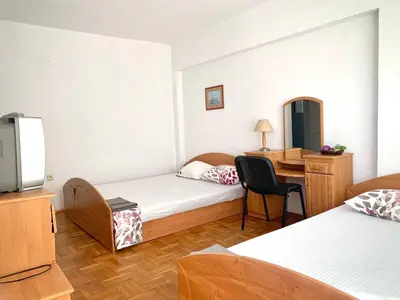 a hotel room with two beds and a desk at Тедис хоум in Burgas City