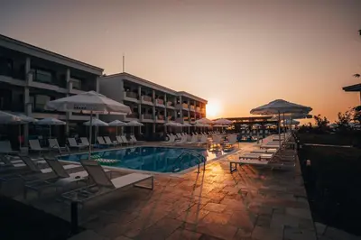 a pool with chairs and umbrellas next to a hotel at Apolonia Resort in Sozopol