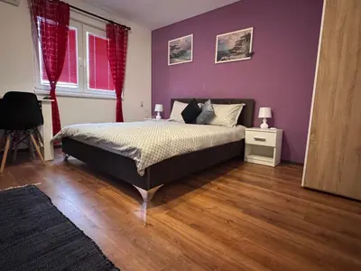 a bedroom with a bed with purple walls and wooden floors at The Central Studio in Burgas City