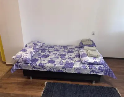 a bed in a room with a purple and white blanket at The Central Studio in Burgas City