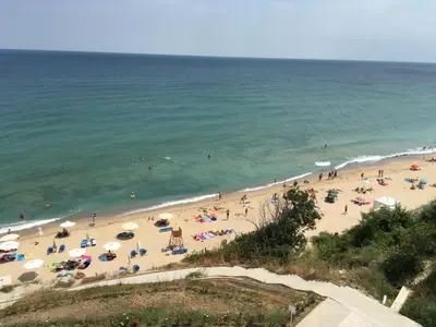 a group of people on a beach with umbrellas at HPManagement Byala Beach Residence Apartments in Byala