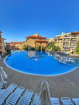 a large swimming pool with white chairs and buildings at Paradise Dreams Studio in Sveti Vlas