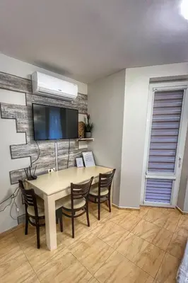 a dining room with a table and chairs and a tv at Paradise Dreams Studio in Sveti Vlas