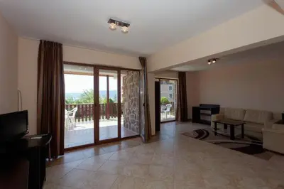 a living room with a couch and a television and a balcony at Вили Vemara club in Byala