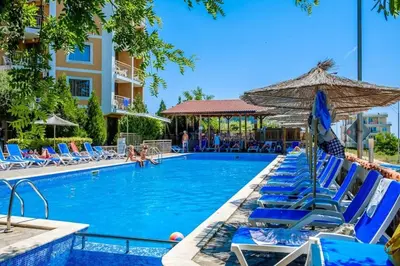a swimming pool with blue chairs and an umbrella at Вили Vemara club in Byala