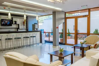 a living room with white furniture and a kitchen at Вили Vemara club in Byala