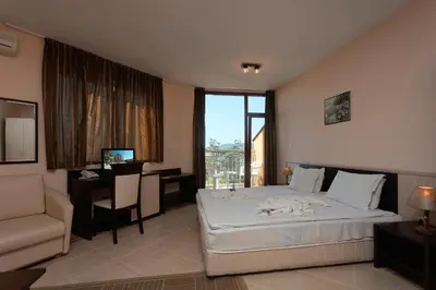 a bedroom with a bed and a desk and a window at Вили Vemara club in Byala
