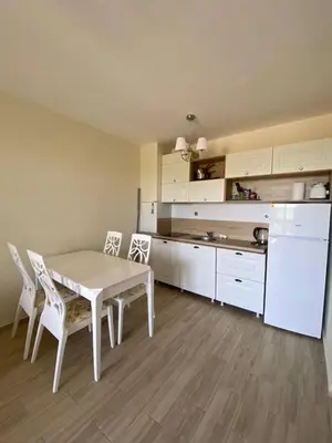 a kitchen with a white table and chairs in a room at Апартамент Cascadas in Sunny Beach