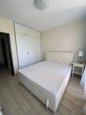 a bedroom with a white bed and a white cabinet at Апартамент Cascadas in Sunny Beach