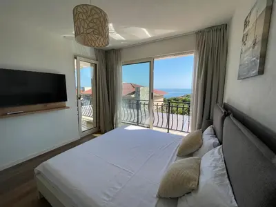 a bedroom with a bed and a balcony with a television at Coral Bay Luxury Villa by Lozenets Luxury Villas in Lozenets