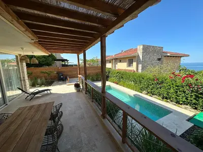a patio with a wooden table and a swimming pool at Coral Bay Luxury Villa by Lozenets Luxury Villas in Lozenets