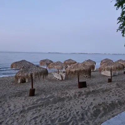 a group of straw umbrellas on a beach at Villa Sardinia Sveti Vlas Studio in Sveti Vlas