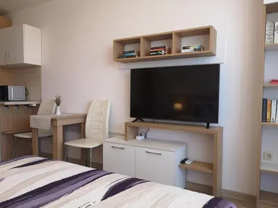 a bedroom with a bed and a flat screen tv at South Beach Apartment in Nesebar