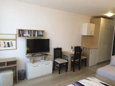 a small living room with a tv and a table and chairs at South Beach Apartment in Nesebar