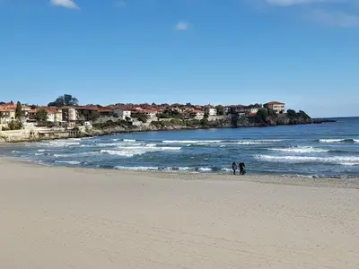 two people standing on a beach near the ocean at Трёхкомнатные роскошные апартаменты у моря в Санта Марина in Sozopol
