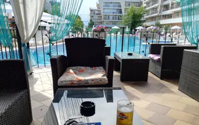 a patio with chairs and a table with a glass of beer at Grand Kamelia Apartment in Sunny Beach