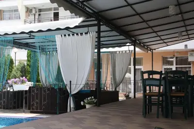 a pergola over a pool with a table and chairs at Grand Kamelia Apartment in Sunny Beach
